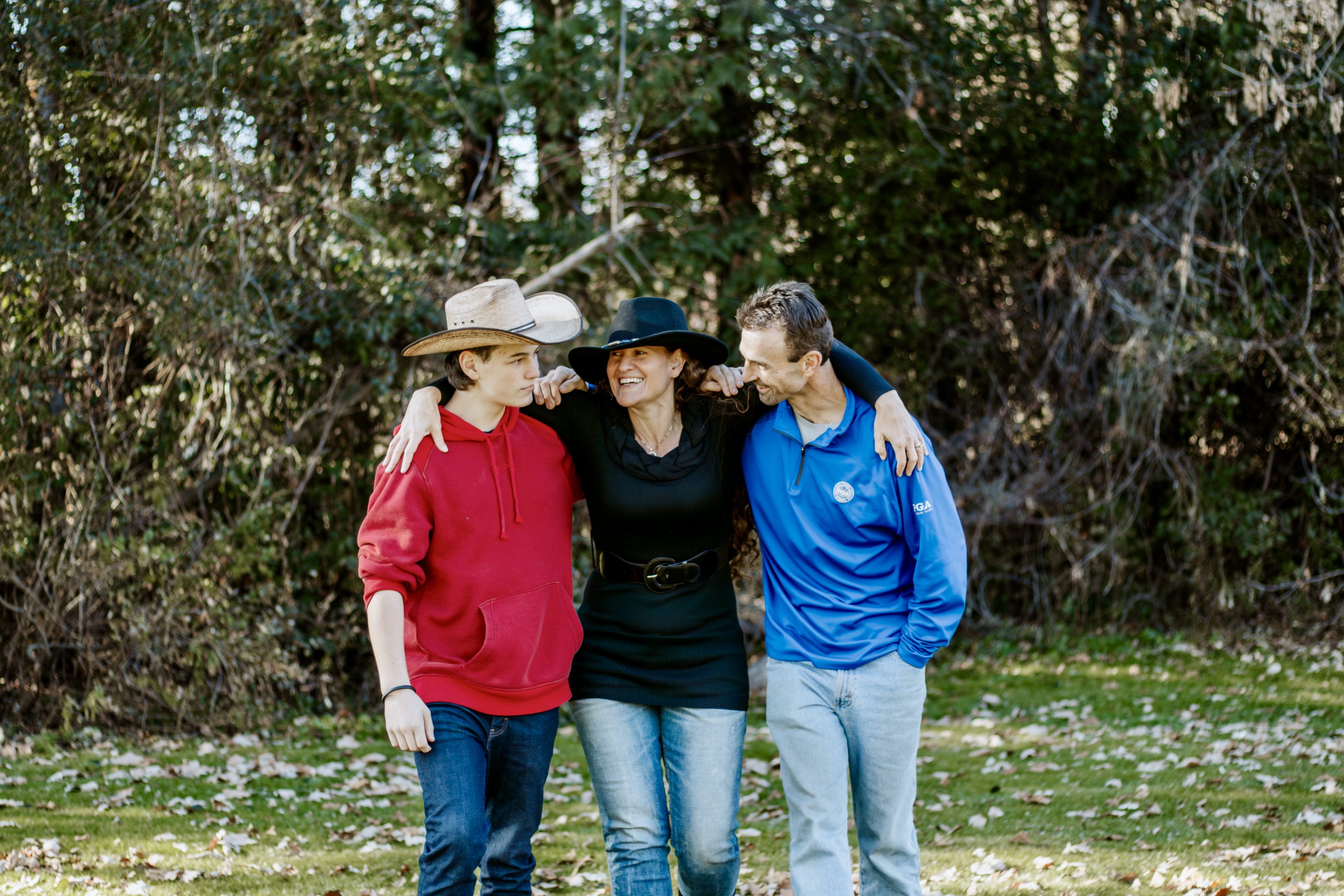 Three friends stand closely together outdoors, smiling and enjoying each other's company.
